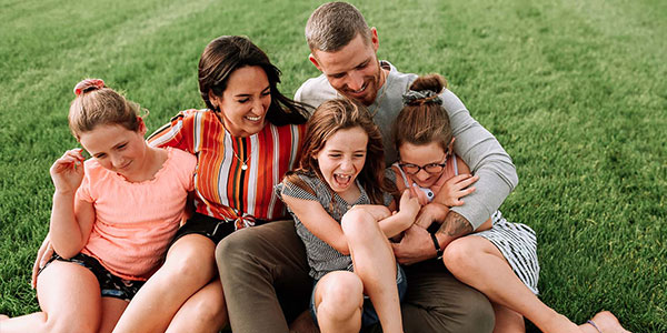 Jeune famille avec leurs enfants qui s'amusent sur une belle pelouse verte