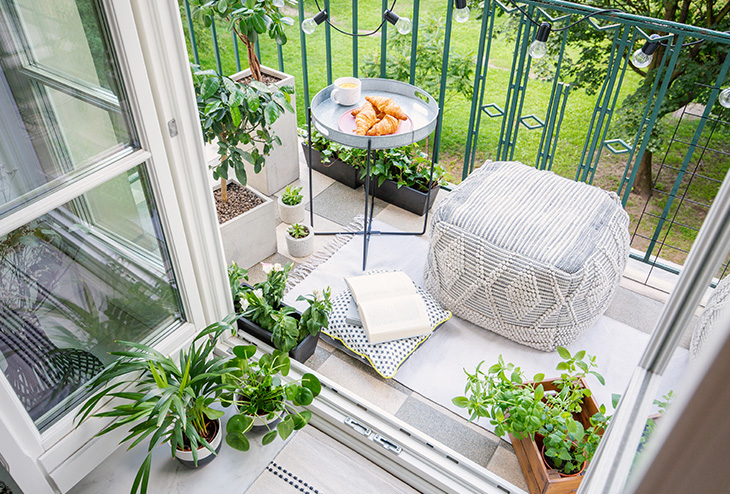 Petit balcon bien aménagé avec des plantes et du mobilier de jardin confortable