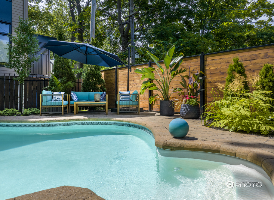 Mobilier de jardin moderne avec des coussins bleus sur le bord d'une piscine creusée
