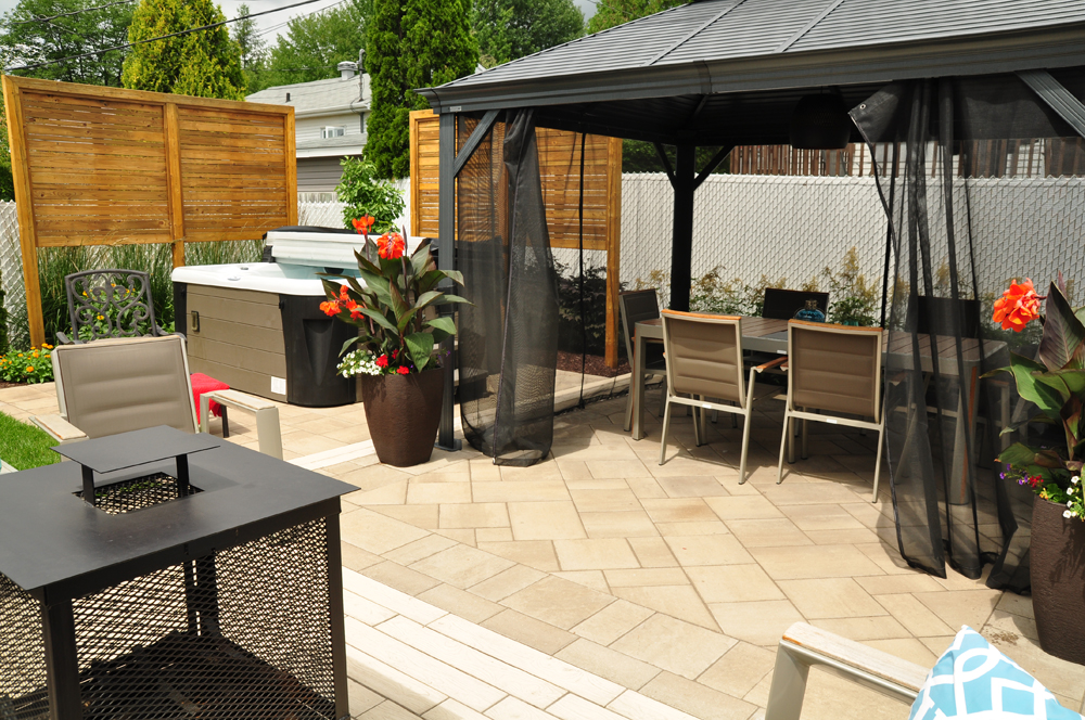 Terrasse en bois avec des plantes colorées menant à un espace détente, reflétant un aménagement multifonctionnel de cour arrière.