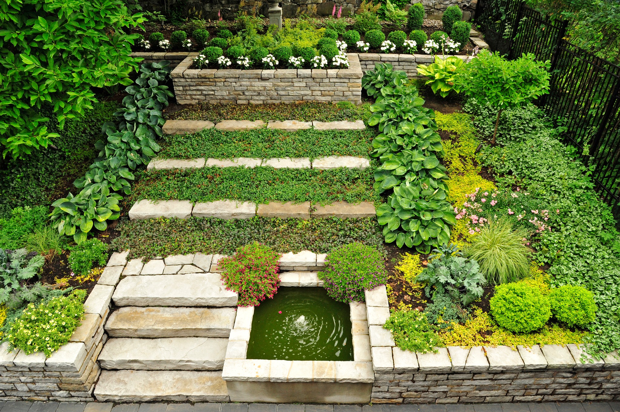 Bassin ornemental intégré à un jardin urbain avec blocs de pierre naturelle