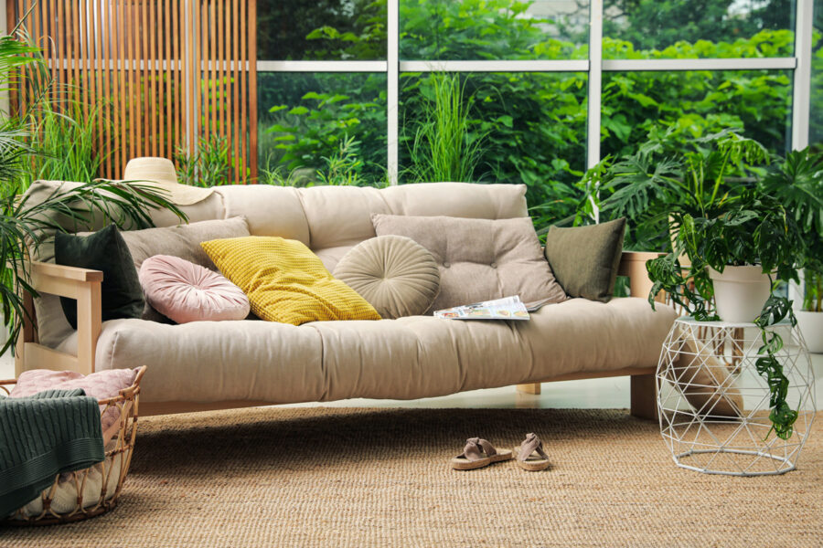 Solarium moderne avec divan beige et plantes tropicales, parfait pour la détente toute l’année