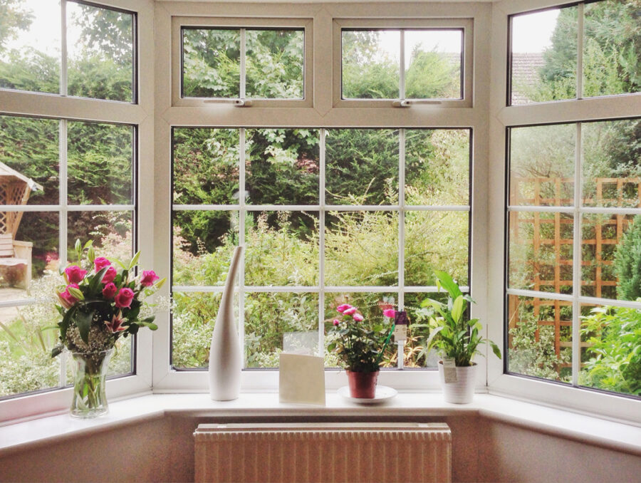 Baie vitrée dans un solarium quatre saisons avec vue verdoyante et plantes en pots