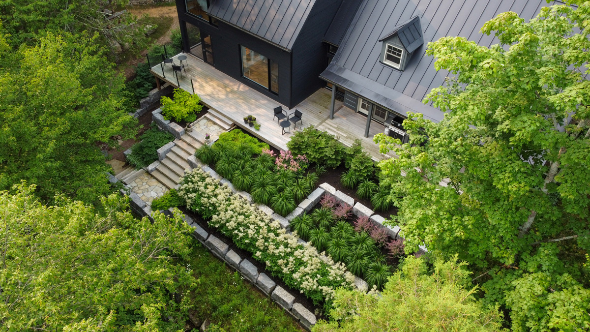 Terrasse entourée d’arbres matures et de buissons fleuris