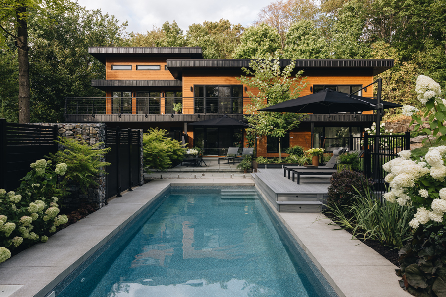 Piscine rectangulaire avec terrasse en matériaux sobres dans un aménagement paysager moderne